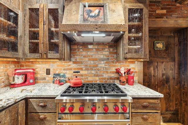 kitchen with stainless steel range, light stone countertops, and wall chimney range hood