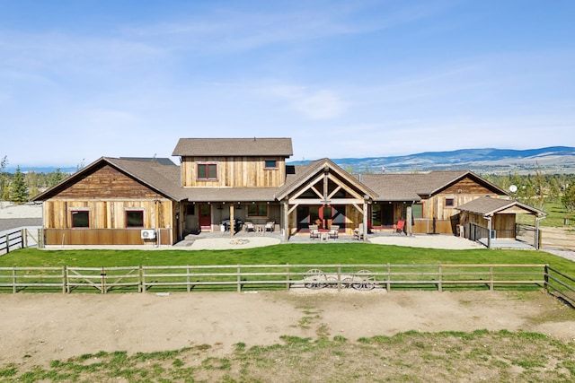 view of front of property featuring a mountain view, a patio area, a front yard, and a rural view