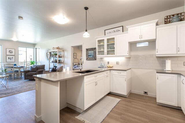 100 Woodlands Way Unit P-204, Kalispell, MT 59901 - kitchen with decorative light fixtures, tasteful backsplash, light hardwood / wood-style flooring, white cabinets, and sink