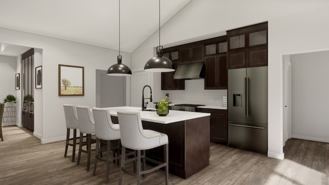 kitchen featuring decorative light fixtures, backsplash, light hardwood / wood-style flooring, high quality fridge, and a center island with sink