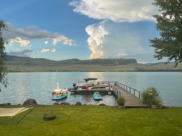 dock area with a yard and a water and mountain view