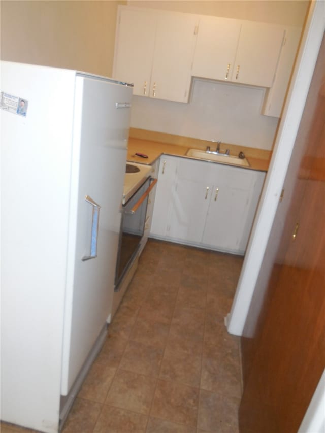 kitchen with white cabinets, range, sink, and light tile flooring