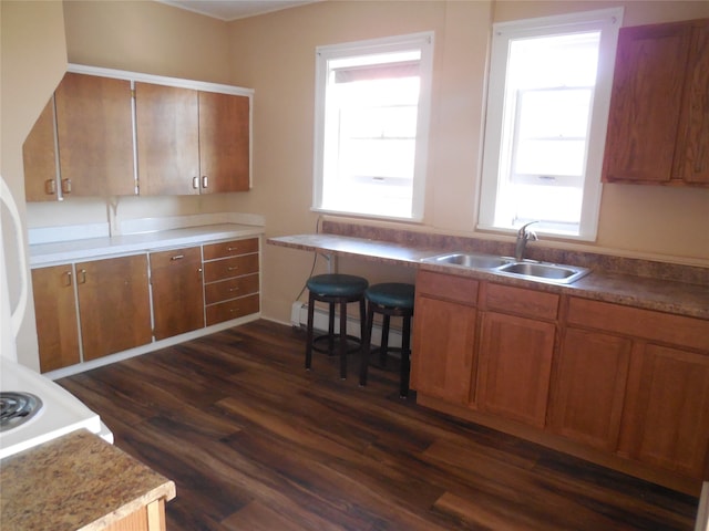 kitchen with a kitchen breakfast bar, baseboard heating, dark hardwood / wood-style floors, and sink