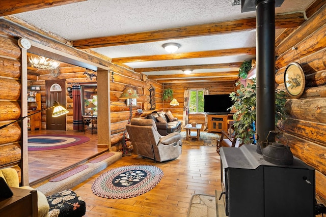 living room featuring wood-type flooring, a wood stove, beamed ceiling, and a textured ceiling