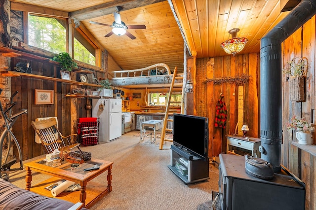 carpeted living room with a wood stove, wood ceiling, vaulted ceiling with beams, ceiling fan, and wooden walls