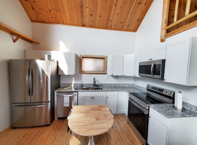 kitchen with white cabinets, a high ceiling, appliances with stainless steel finishes, and light hardwood / wood-style floors