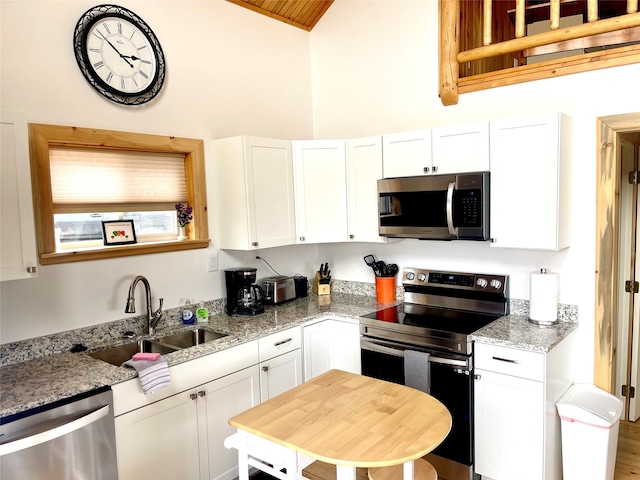 kitchen with stainless steel appliances, light stone counters, and white cabinets