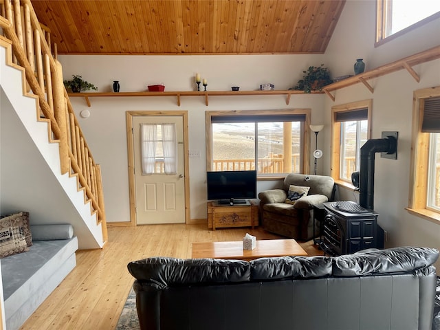 living room with wooden ceiling, a wood stove, light wood-type flooring, and a wealth of natural light