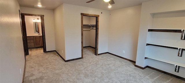 unfurnished bedroom featuring ensuite bathroom, light colored carpet, ceiling fan, a spacious closet, and a closet