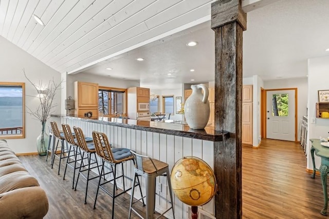 17431 Fishing Rock Ln, Bigfork, MT 59911 - kitchen with white microwave, wood finished floors, decorative columns, light brown cabinets, and a kitchen breakfast bar
