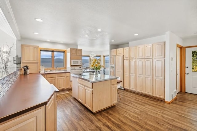 kitchen featuring a center island, recessed lighting, white microwave, light brown cabinets, and wood finished floors