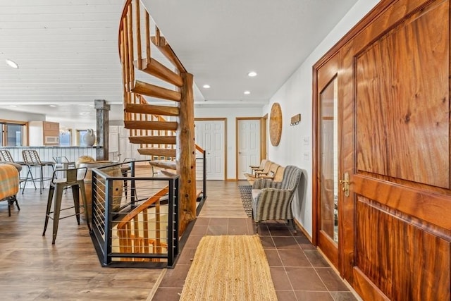 hall featuring recessed lighting, dark tile patterned floors, baseboards, and stairs