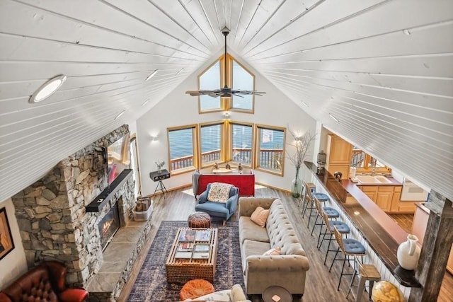 living room featuring lofted ceiling, a fireplace, baseboards, and wood finished floors