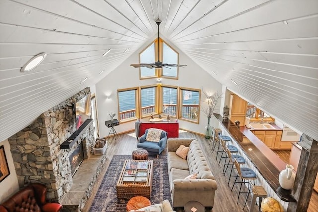 17431 Fishing Rock Ln, Bigfork, MT 59911 - living area with a stone fireplace, wood finished floors, lofted ceiling, and a ceiling fan