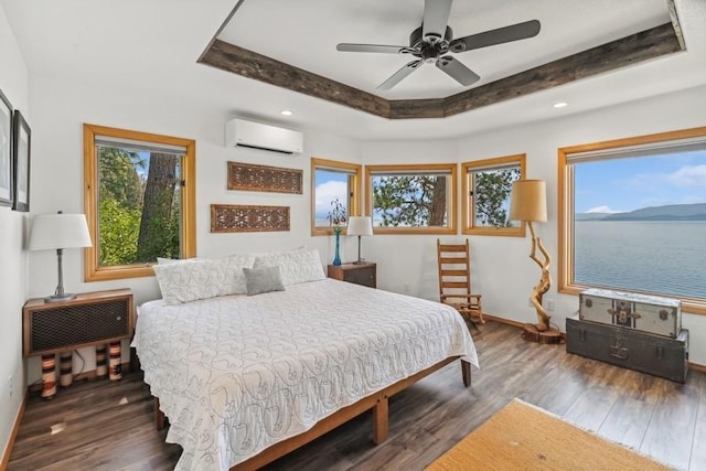 bedroom featuring a tray ceiling, wood finished floors, baseboards, and a wall mounted AC