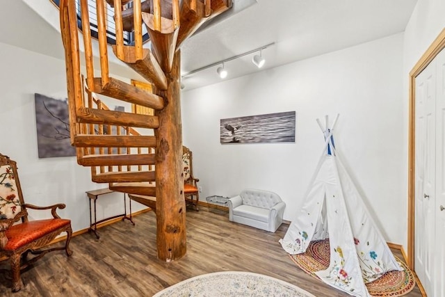 staircase featuring track lighting, wood finished floors, and baseboards