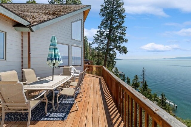 deck with a water view and outdoor dining space