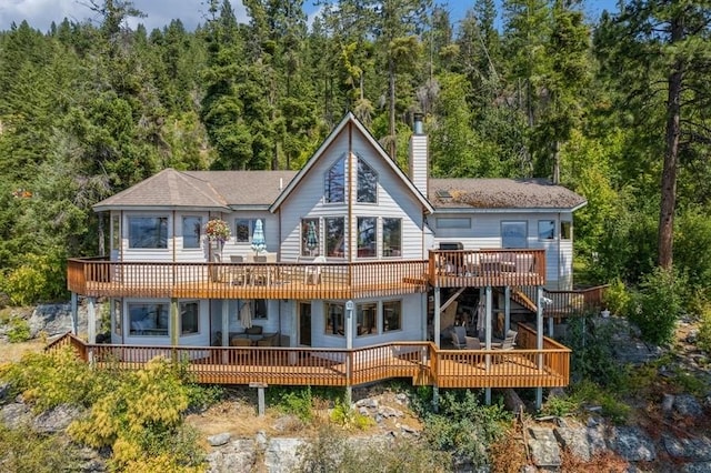 back of property with a chimney and a wooden deck