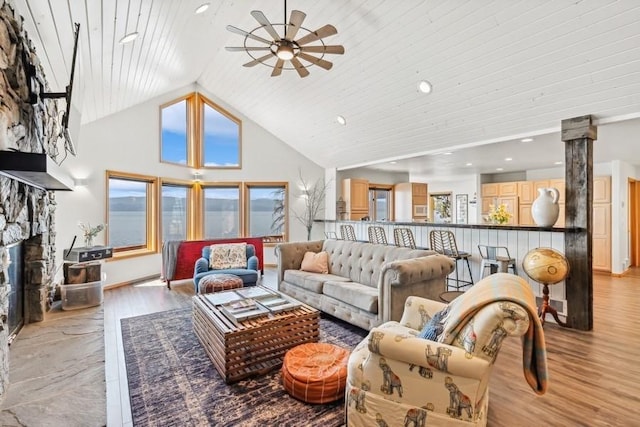 living area featuring high vaulted ceiling, wooden ceiling, a fireplace, light wood-style floors, and decorative columns