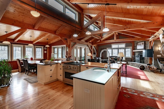 kitchen featuring high end stainless steel range, wooden ceiling, light hardwood / wood-style floors, hanging light fixtures, and an island with sink