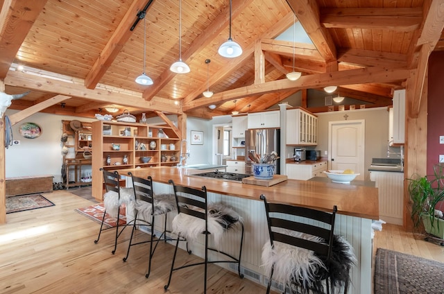 kitchen featuring wooden counters, appliances with stainless steel finishes, pendant lighting, beamed ceiling, and white cabinets