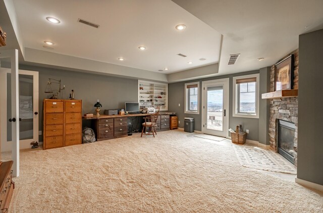 office space with a fireplace, built in shelves, and carpet flooring