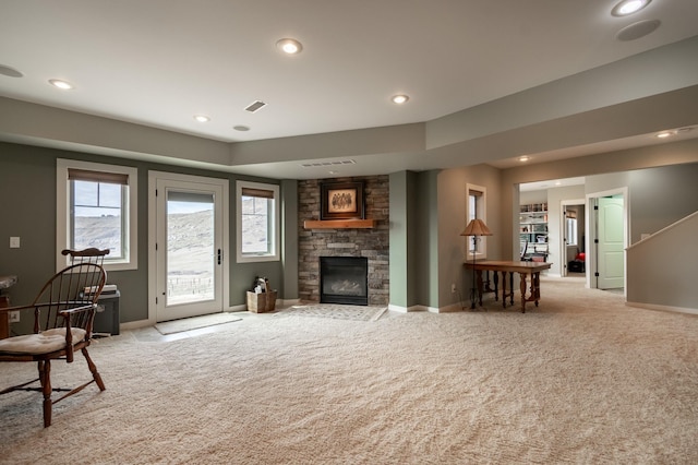 living room featuring a stone fireplace and light colored carpet