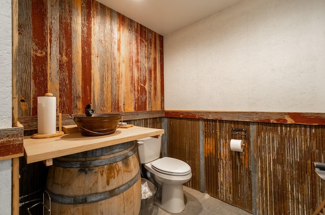 bathroom with toilet and wood walls