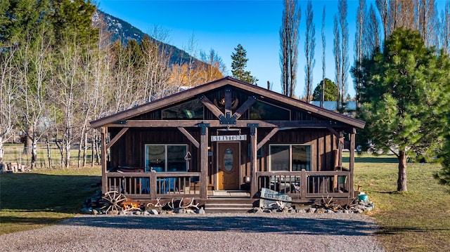 view of front of house featuring covered porch, a front yard, and a mountain view