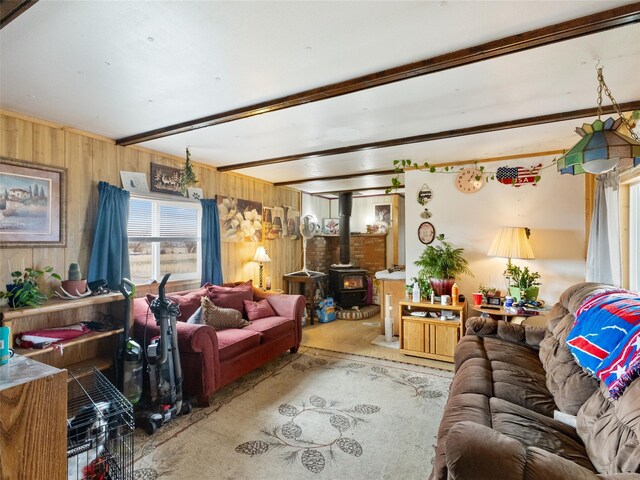 living room featuring wooden walls, light carpet, a wood stove, and beamed ceiling