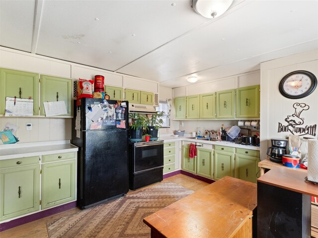 kitchen with black fridge, range with electric cooktop, premium range hood, and green cabinets