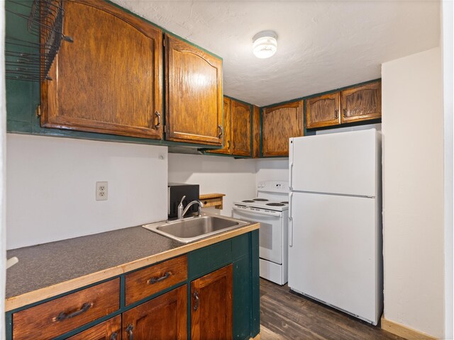 kitchen featuring white appliances, dark wood-type flooring, and sink