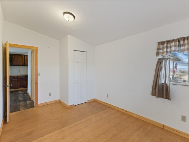 spare room featuring lofted ceiling and light hardwood / wood-style flooring