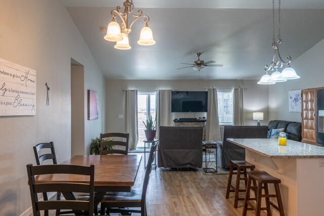 dining area featuring dark hardwood / wood-style floors, ceiling fan with notable chandelier, and lofted ceiling