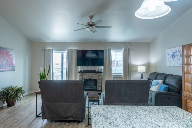 living room with a fireplace, wood-type flooring, and ceiling fan