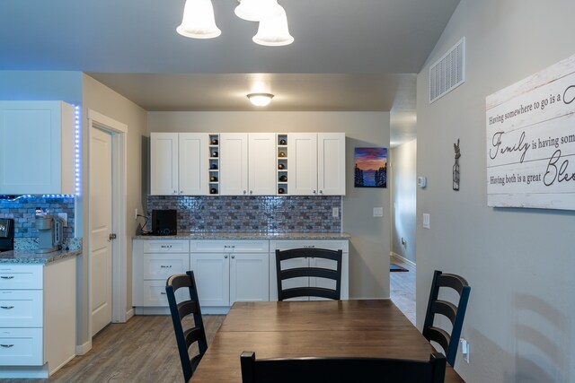 interior space with white cabinetry, hardwood / wood-style flooring, and backsplash