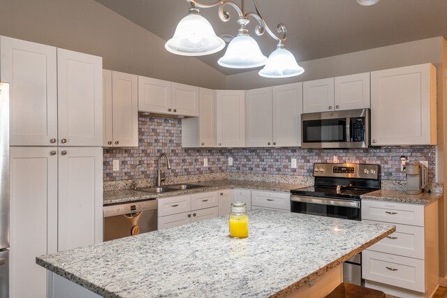 kitchen featuring tasteful backsplash, stainless steel appliances, decorative light fixtures, sink, and white cabinetry