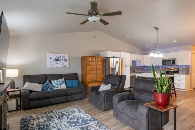 living room featuring ceiling fan, light hardwood / wood-style floors, and lofted ceiling