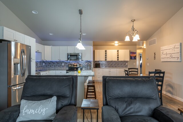 kitchen with appliances with stainless steel finishes, white cabinetry, and lofted ceiling