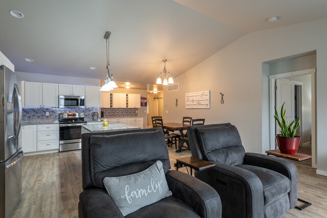 living room featuring hardwood / wood-style flooring, lofted ceiling, and an inviting chandelier