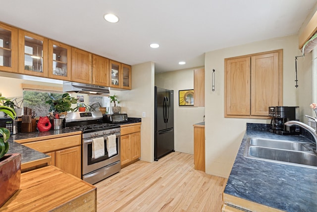 kitchen featuring black refrigerator, light wood-type flooring, gas stove, and sink