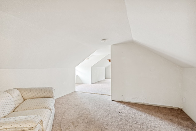 additional living space featuring vaulted ceiling and carpet flooring