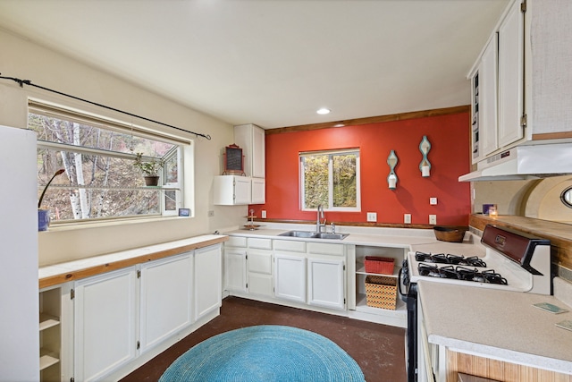 kitchen with white cabinets, gas range oven, light countertops, and a sink