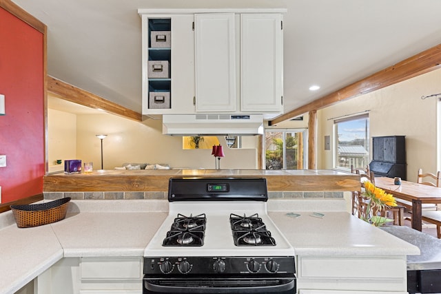 kitchen featuring kitchen peninsula, white cabinetry, gas range gas stove, and range hood