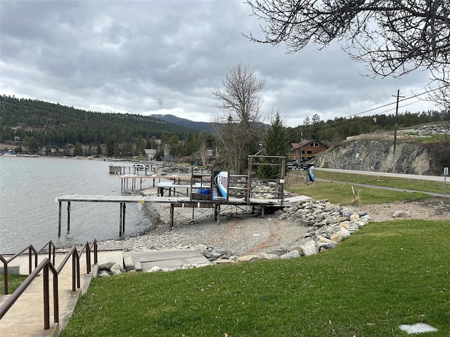 dock area with a water and mountain view and a lawn