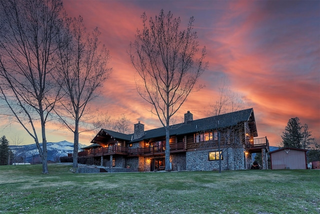 back house at dusk featuring a mountain view and a yard