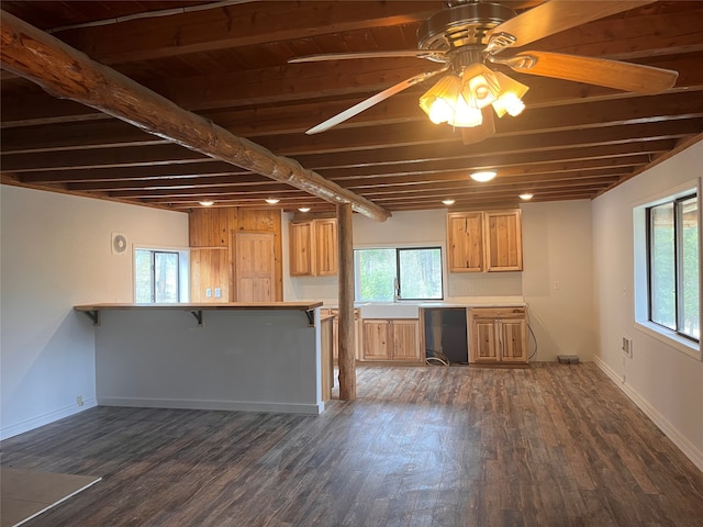 kitchen featuring dark hardwood / wood-style flooring, ceiling fan, beamed ceiling, and a kitchen bar