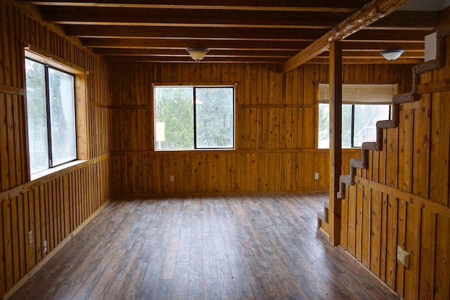 spare room featuring beamed ceiling, a healthy amount of sunlight, and dark wood-type flooring