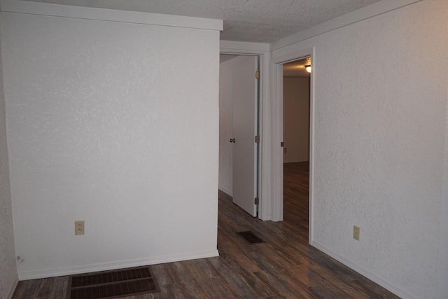 empty room featuring dark hardwood / wood-style floors and a textured ceiling