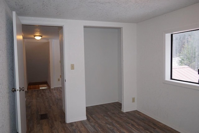 unfurnished bedroom featuring dark hardwood / wood-style flooring and a textured ceiling